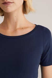 Navyblaues Kurzarmoberteil mit Rundhalsausschnitt und glattem, dehnbarem Stoff. Nahaufnahme, die den Kragen und die Schulternaht hervorhebt.