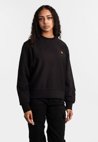 Zwarte sweatshirt met een geribbelde ronde hals, lange mouwen en een relaxte pasvorm. Heeft een klein logo in geel en rood op de borst.