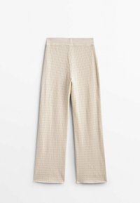 Crème-kleurige brede broek met wafelstructuur en elastische tailleband, plat gelegen op een witte achtergrond.