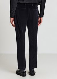 Marineblaue Samthose mit zwei Gesäßtaschen, geradem Schnitt und glatter Textur. Kombiniert mit glänzenden schwarzen Schuhen.