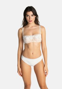 Brassière en dentelle blanche avec un motif floral, en matière semi-transparente, et bretelles ajustables, associée à un slip de bikini blanc assorti.