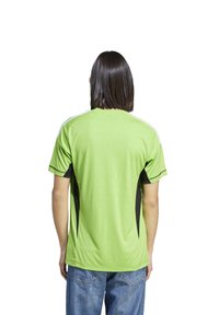 Camiseta deportiva verde con paneles laterales negros y acentos blancos. Mangas cortas, cuello redondo y tejido ligero y texturizado.