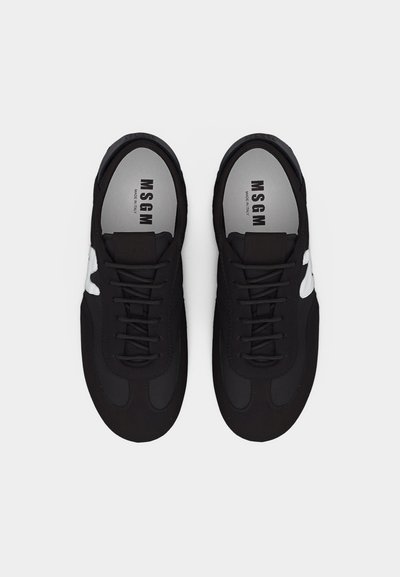 Ζεύγος μαύρων αθλητικών παπουτσιών MSGM με λευκό λογότυπο στα πλάγια, μαύρα κορδόνια και γκρι εσωτερικές σόλες με την ετικέτα "MSGM Made in Italy", όπως φαίνεται από πάνω.