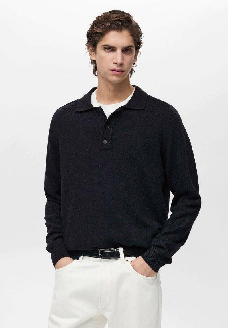 Black knit pullover with a collar, three-button placket, and ribbed cuffs. Worn with white pants. Smooth texture, casual design.