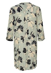 Robe florale avec une base vert clair, ornée de motifs de fleurs noirs et crème. Manches longues et design décontracté et fluide. Texture de tissu douce.