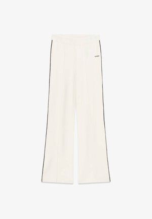 Pantaloni bianchi a gamba larga con strisce laterali nere e logo "GUESS" sulla parte anteriore della coscia superiore.
