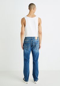 Blå denimjeans med rak passform, blekt utseende och två bakfickor med sömnadsdetaljer. Matchas med en vit linne.