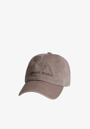 Brązowa bawełniana czapka baseballowa z zakrzywionym daszkiem, z czarnym haftowanym napisem „rethinkit studios” z przodu.