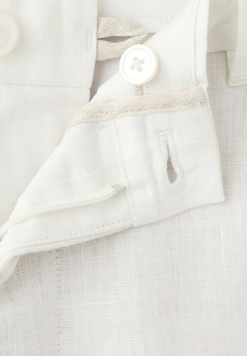 Ceinture de vêtement en lin blanc avec bouton cousu et boutonnière, sur un fond de tissu texturé.