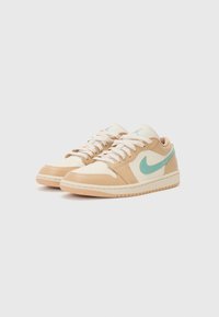 Baskets beige et crème avec un swoosh Nike vert menthe. Matériaux lisses et texturés ; design à lacets ; semelle en caoutchouc avec un motif de traction.