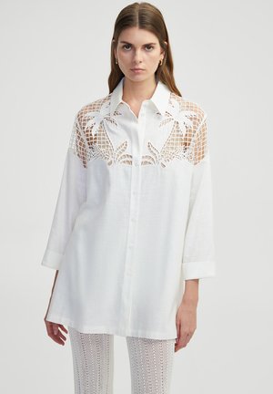 Witte linnen shirt met driekwartmouwen, voorzien van verfijnde uitsnijdingen in kant op de schouders en een klassieke knoopsluiting.