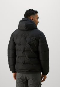 Svart boblejakke med hette, med horisontale quiltede seksjoner og elastiske mansjetter. Glatt tekstur, designet for varme og komfort.