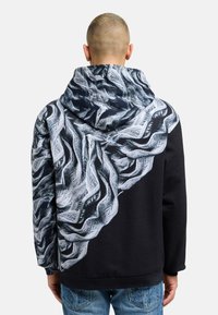 Black hoodie featuring a textured graphic design in white and grey, resembling woven fabric, on the back and hood. Regular fit.