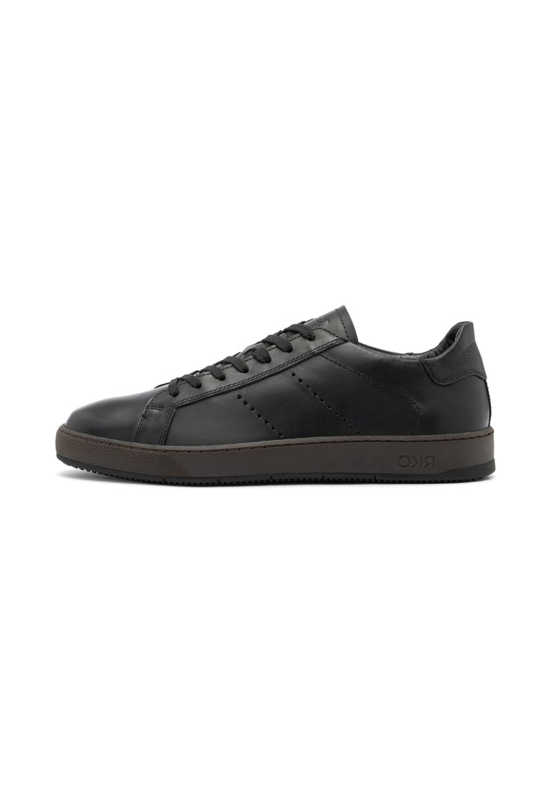 Adidași negri din piele cu talpă din cauciuc brun plat, design subțire, detalii perforate pe laterale și închidere cu șireturi.