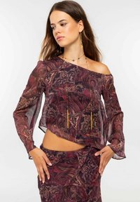 Blusa transparente con escote Bardot y falda a juego en un patrón de paisley burdeos y dorado, con mangas largas y texturas en capas.