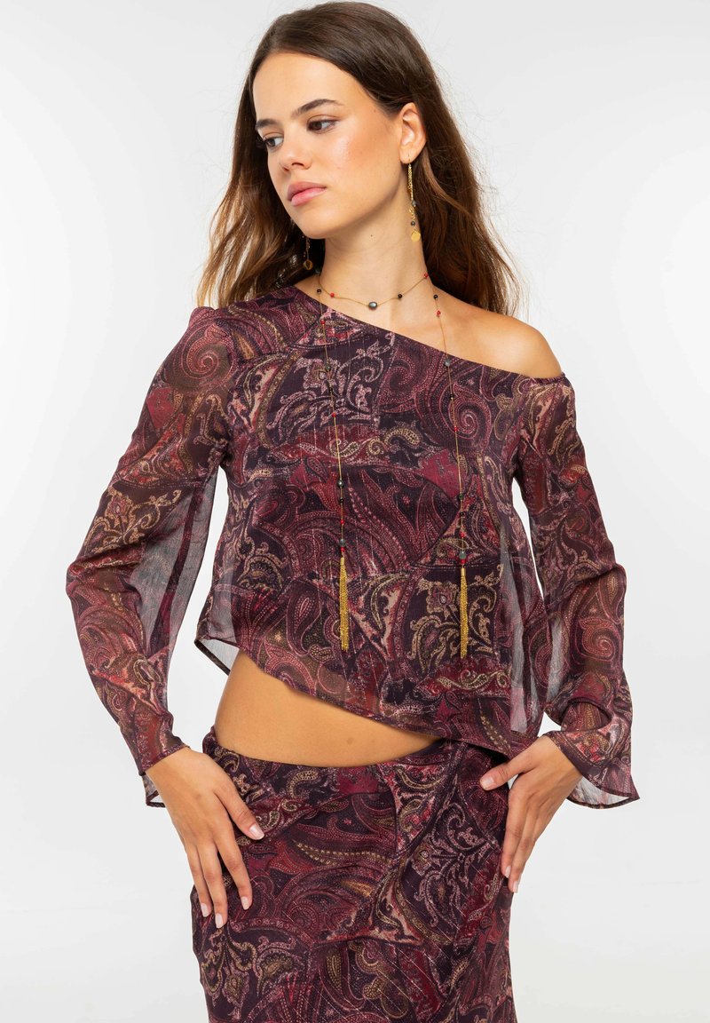 Blusa transparente con escote Bardot y falda a juego en un patrón de paisley burdeos y dorado, con mangas largas y texturas en capas.