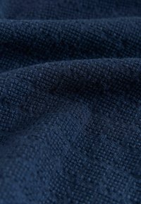 Tissu bleu marine texturé avec un motif tissé. Présente une structure légèrement en relief, mettant en valeur des détails complexes et une finition douce et mate.