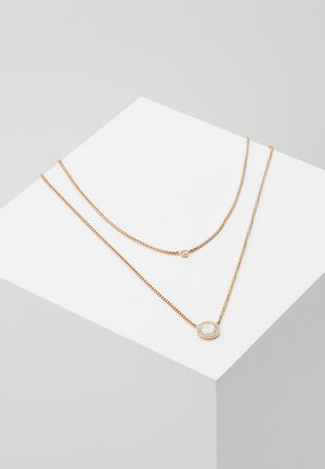 Gold-tone layered necklace featuring a delicate chain and an oval pendant with a light gemstone, set in a round, embellished frame.