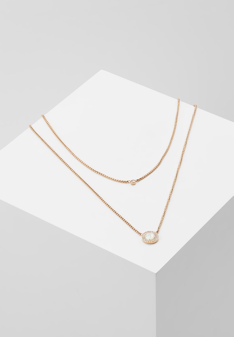 Goldfarbene, mehrlagige Halskette mit einer feinen Kette und einem ovalen Anhänger mit einem hellen Edelstein, der in einem runden, verzierten Rahmen eingefasst ist.