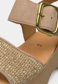 Μπεζ πλατφόρμα πέδιλο με πλεκτό μπροστινό λουράκι, ρυθμιζόμενο σουέντ λουράκι αστραγάλου και χρυσό τετράγωνο πόρπη, μέγεθος 4½ εμφανίζεται εσωτερικά.