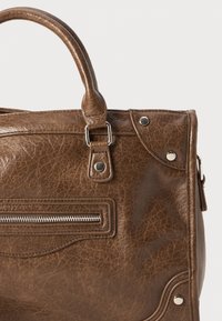 Braune Kunstleder-Handtasche mit strukturiertem Oberflächen, zwei Griffen, silbernen Beschlägen, einer Reißverschlusstasche und dekorativen Nähten.