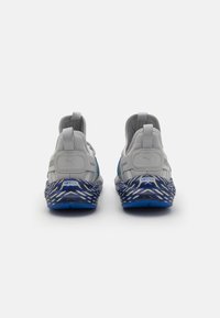 Gray athletic shoes with a textured mesh upper, featuring a blue and white patterned sole, and visible branding on the heel.