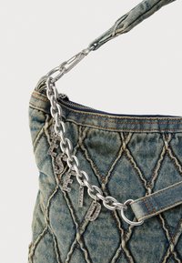 Prošivena traper torbica s naramenicom od srebrnog lanca. Sadrži metalne privjeske u obliku slova i kontrastne narančaste šavove na teksturiranoj površini.