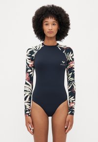 Long-sleeve one-piece swimsuit featuring a navy body and floral-patterned sleeves. Made of stretchy material with a slim fit. Roxy logo on chest.
