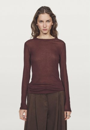 Langærmet top i burgundy gennemsigtig stof med rund halsudskæring. Løs pasform med en jævn kant, parret med højtsiddende brune bukser.
