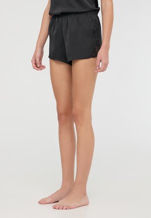 Czarne satynowe szorty z koronkowym wykończeniem, posiadające elastyczny pas i luźny krój, sięgające do górnej części uda. Bez kieszeni.