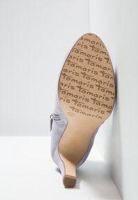 Harmaat mokka korkeakorkoiset kengät, joissa on terävä kärki ja sivuvetoketju, beige pohja, jossa on leimattu brändin nimi "Tamaris" ja koko 37.