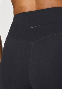 Μαύροι κολάν με ψηλή μέση, φτιαγμένοι από μαλακό και ελαστικό ύφασμα. Διαθέτουν αδιάκοπη σχεδίαση με ένα μικρό γκρι λογότυπο Nike στο κέντρο της μέσης.