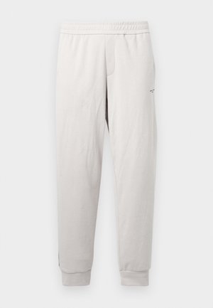 Világosszürke melegítőnadrág rugalmas derékkal, oldalsó zsebekkel, bordázott mandzsettákkal és diszkrét márkajelzéssel a lábon, puha anyagból készült.