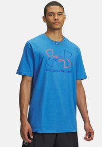 Camiseta de algodón azul con mangas cortas, que presenta un gran logo multicolor de Under Armour en el pecho. Ajuste casual, textura suave.