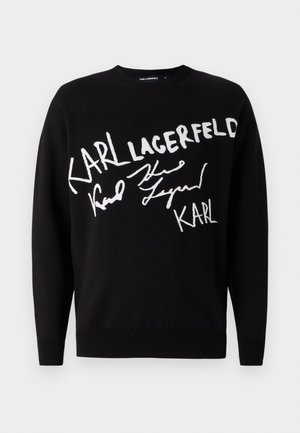 Svart genser med hvit brodert tekst som leser "KARL LAGERFELD" og et signaturdesign. Enkel rund hals og langermede.