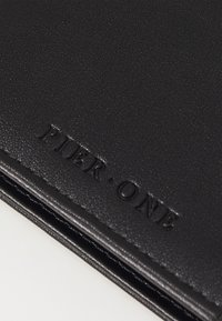 Cartera negra texturizada hecha de material sintético, con el logo "PIER•ONE" en relieve a lo largo del borde y detalles de costura.