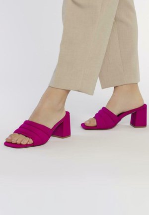 Mules fucsias de punta abierta con tres tiras acolchadas y un tacón cuadrado, fabricados con un tejido suave y de textura lisa.