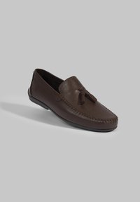 Braune Leder-Mokassinschuhe mit strukturierten Oberflächen, genähten Details und einer Quasten-Akzentuierung. Weiche Sohle und Slip-On-Design.