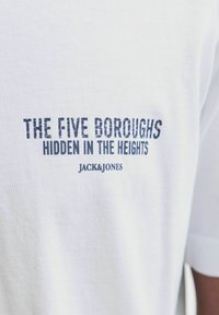 White cotton t-shirt featuring dark blue text: "THE FIVE BOROUGHS HIDDEN IN THE HEIGHTS" and "JACK & JONES" logo. Short sleeves, crew neck design.