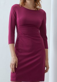 Těsně padnoucí šaty ke kolenům v živé magentové barvě s rukávy po tři čtvrtiny, s nařaseným detailem v pase a hladkou texturou.