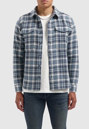 Blauw-wit geruite shirt van zachte stof, met twee borstzakken, knopen aan de voorkant en lange mouwen, gelaagd over een wit T-shirt.