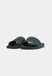 Black rubber slide sandals with wide straps featuring the brand name in a bold, contrasting print. Textured footbed and flat sole.