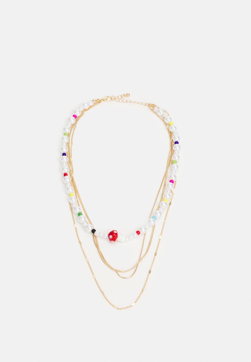Colar em camadas em tom de dourado, com pérolas falsas brancas, contas coloridas e um detalhe de cogumelo vermelho. Correntes texturizadas aumentam o interesse visual.