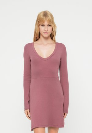 Langærmet kjole i lavendel farve med dyb V-udskæring, tætsiddende overdel og udvidet nederkant. Fremstillet af blødt stof med let stretch.