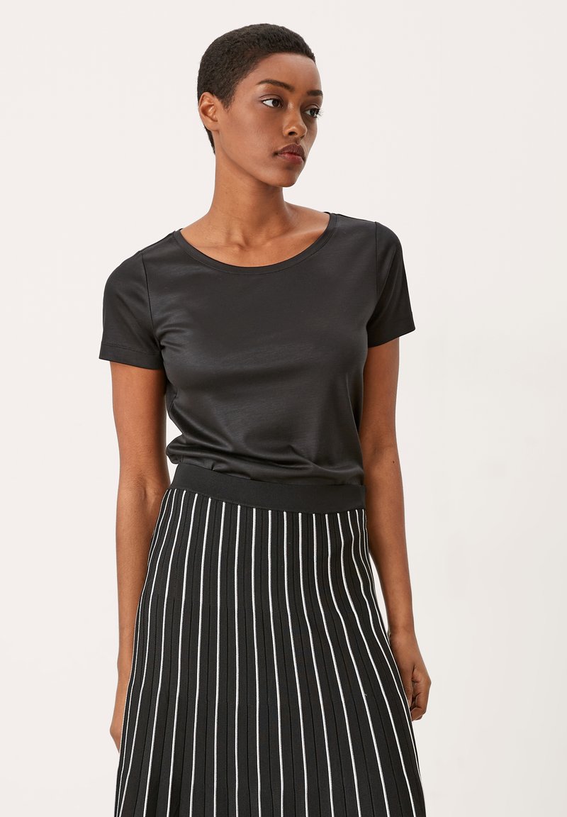 Zwart T-shirt met korte mouwen van gladde stof, gecombineerd met een zwart-wit gestreepte midi-rok met een aansluitende tailleband en verticale lijnen.