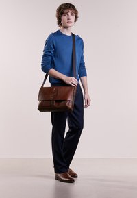 Borsa a tracolla in pelle marrone con chiusura a pattina, caratterizzata da una forma rettangolare semplice e una tracolla rimovibile.