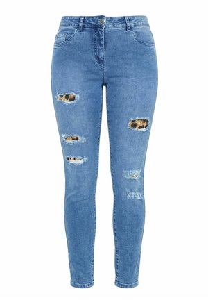 Jean skinny bleu avec tissu imprimé léopard visible à travers plusieurs déchirures usées sur l'avant des cuisses et des genoux.