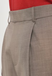 Light brown tailored trousers with a textured fabric, featuring a flat front, side pockets, and a clean waistband design.