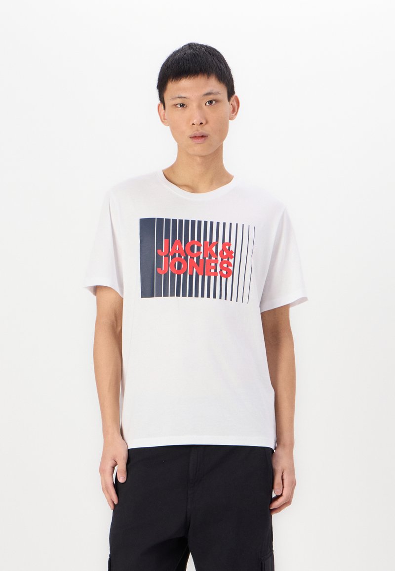 Tricou alb din bumbac, cu un graphic dreptunghiular navy, având linii verticale și text roșu "JACK & JONES" centrat pe partea din față. Mâneci scurte.