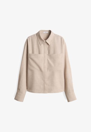 Chemise beige à col, à manches longues, avec deux poches avant, fabriquée en tissu texturé, présentant un ourlet droit et un design minimaliste.